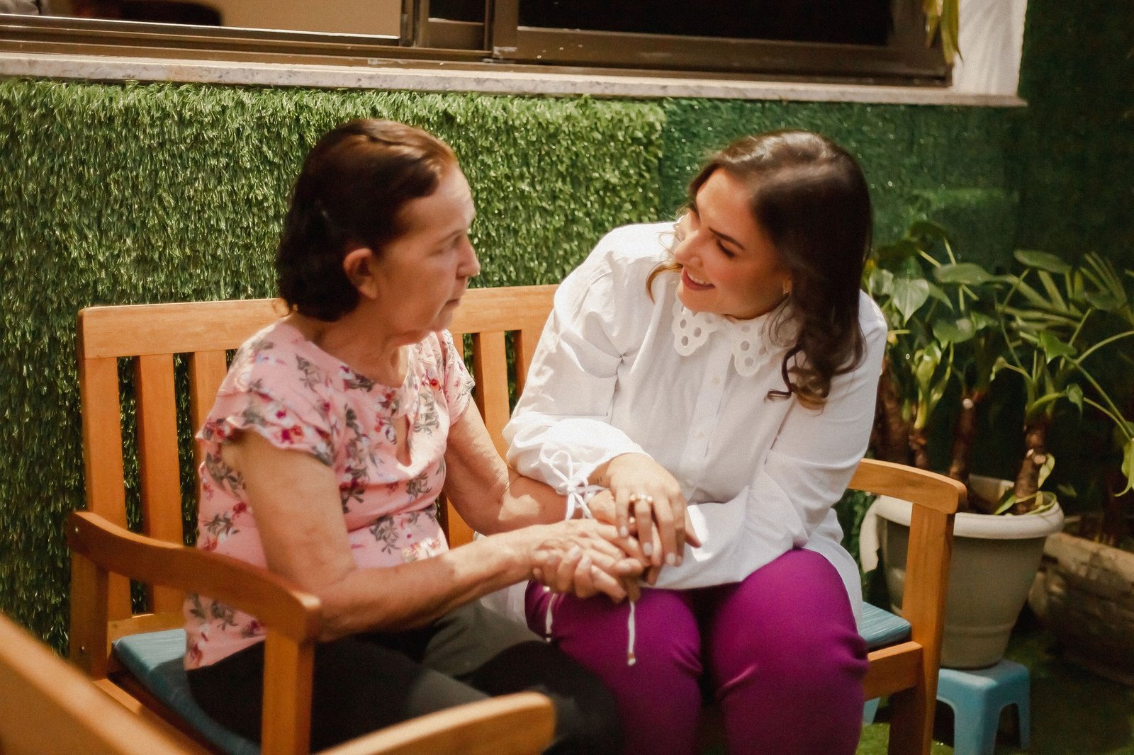 Cuidadora ao lado de uma idosa no jardim